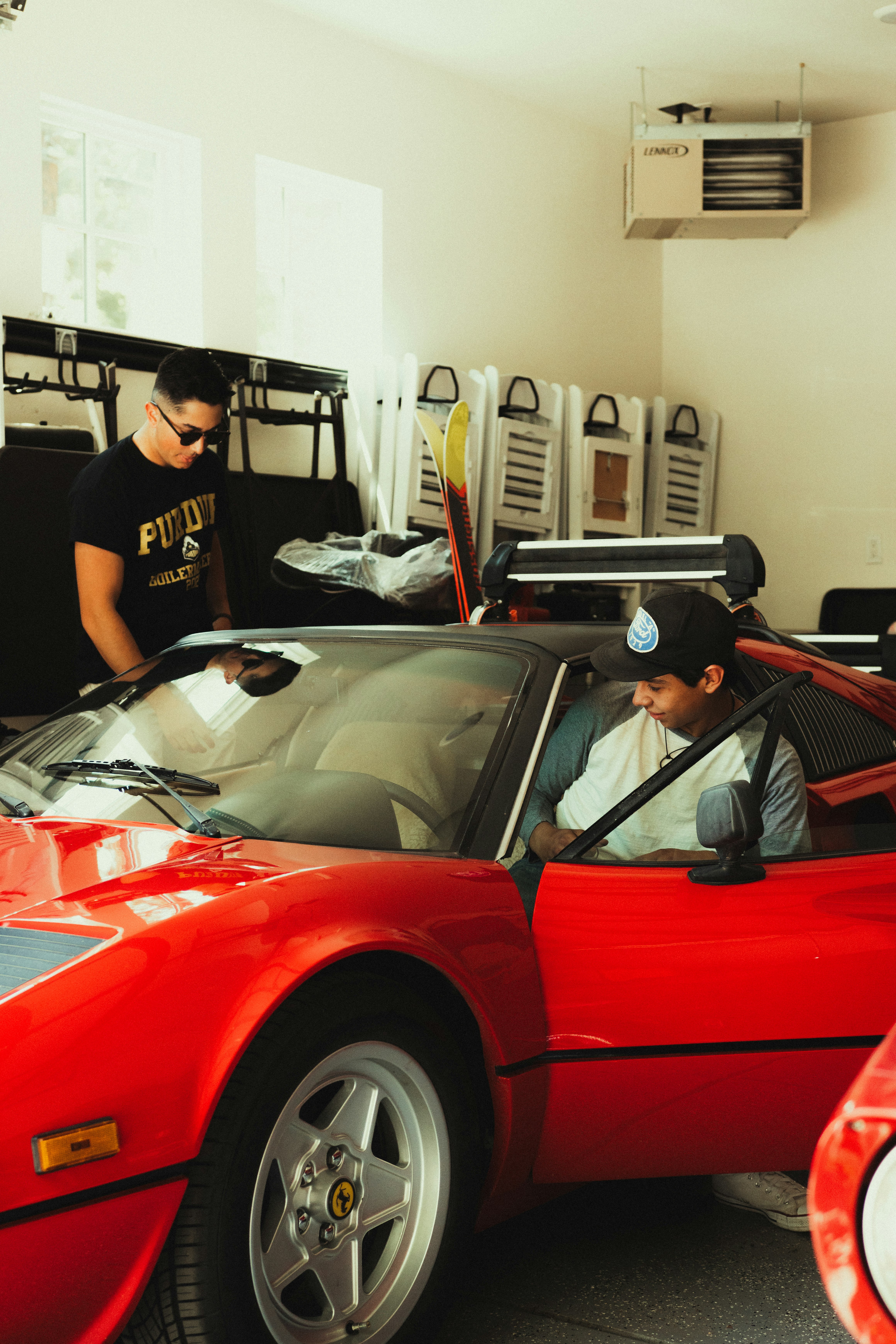 man in black crew neck t-shirt standing beside red car